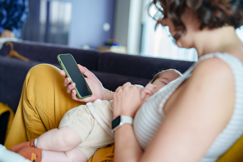 Mother breastfeeding her baby and using mobile phone at home. - stock photo
A day of a new born baby at home with his all family.