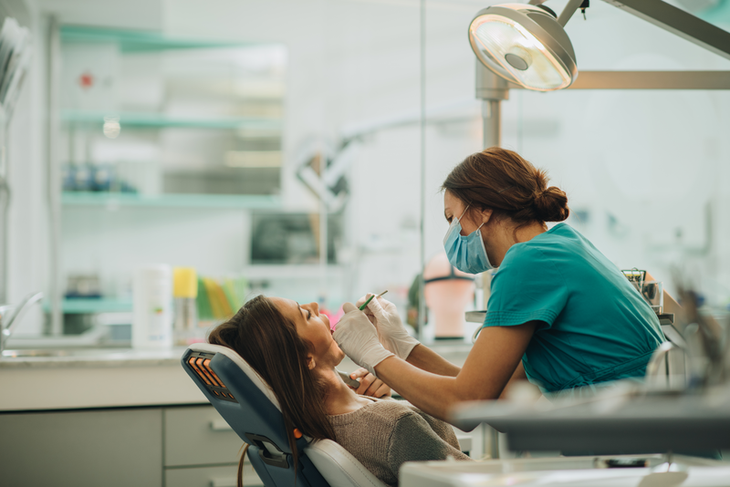 Young woman having her teeth checked during appointment at dentist's office. - stock photo
Female dentist examining young woman's teeth.
