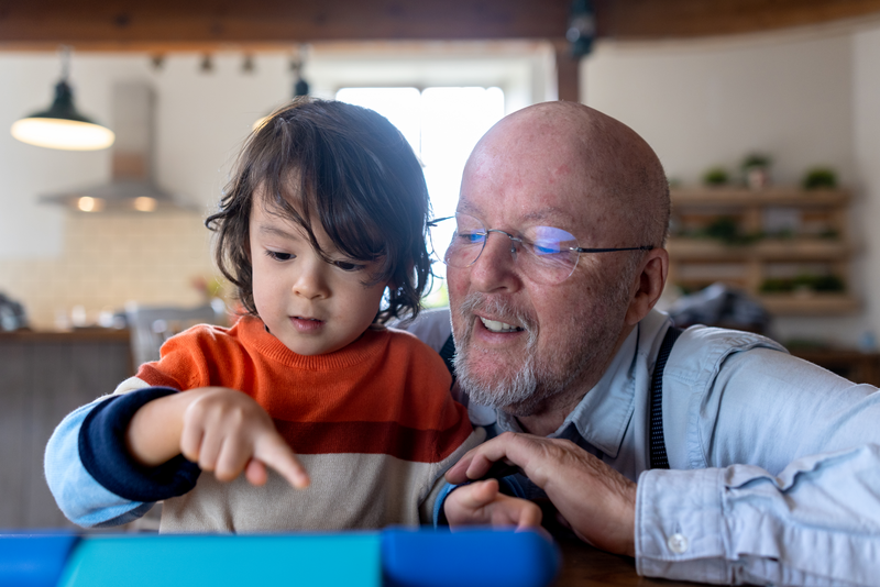 Showing Grandad Something on Digital Tablet - stock photo
A full shot of a grandfather and grandson both playing and looking at a digital tablet sitting down at the kitchen table. The grandad has his arm around his grandson.